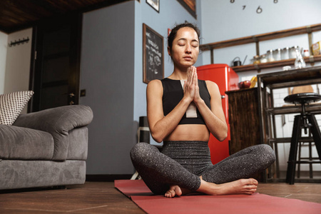 美丽的健康女人在家里坐在健身垫上做瑜伽运动