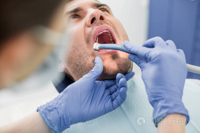牙科医生在牙科诊所与病人合作时,用口罩钻牙