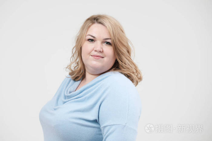 年轻的肥胖妇女在休闲蓝色衣服在白色背景在演播室.身体阳性