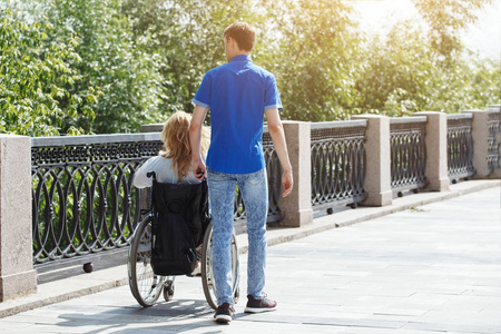 坐轮椅的女人和男朋友在城市夏季公园散步