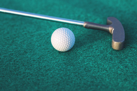迷你高尔夫双向推杆俱乐部和球在绿色表面与复制空间