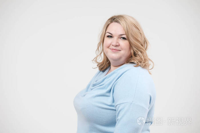 年轻的肥胖妇女在休闲蓝色衣服在白色背景在演播室.身体阳性