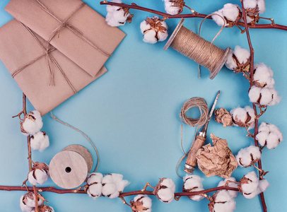 扁平的女性浅蓝色背景与棉花花的分支。棉, 礼品盒, 黄麻绳衣架。平面铺设, 复制空间