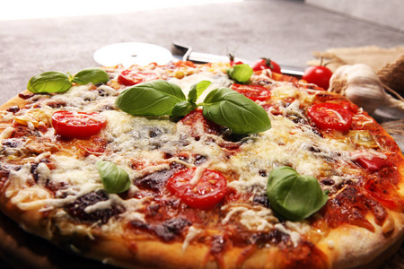 意大利素食比萨饼，上面有融化的奶酪红西红柿和绿罗勒，由奶酪番茄和红樱桃西红柿装饰。