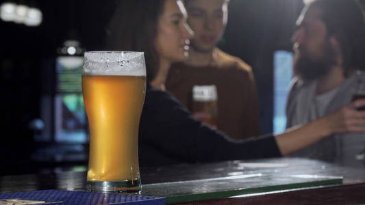 有选择地关注啤酒杯, 背景是酒吧里的人喝酒