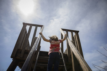 小女孩爬到一个木制的观察塔在湿地