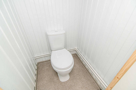 明亮的公共厕所房间的照片，里面站着一个白色的马桶