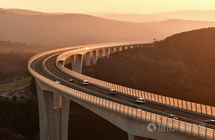 汽车在美丽的夕阳下行驶在高速公路高架桥上