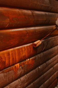 画家用油漆滚筒画一堵木房子的墙