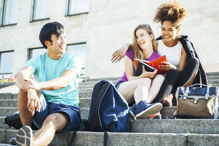 可爱的青少年小组在大学大厦与书拥抱, 多样性国家学生生活方式