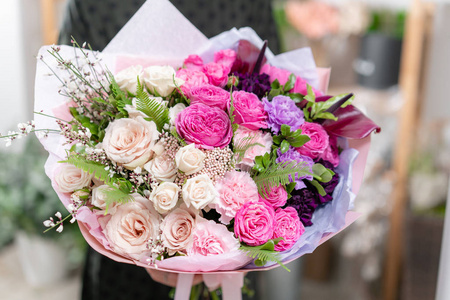 颜色的。美丽的新鲜切花混合鲜花在女人的手。花店的花商的作品。精致的柔和色调颜色