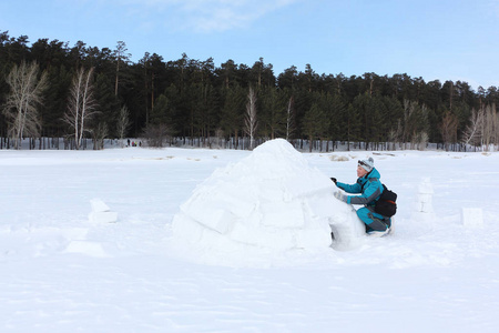 穿着温暖衣服的幸福女人在冬天的俄罗斯新西伯利亚的雪地上搭建一个冰屋