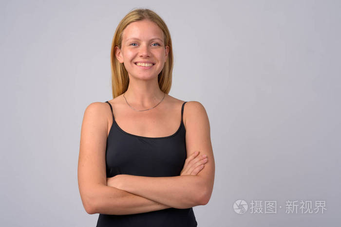 年轻的愉快的金发碧眼的妇女的肖像微笑与胳膊交叉