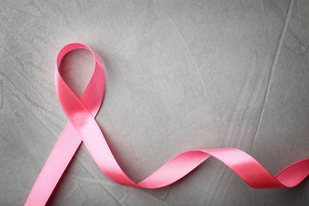 粉红色丝带在灰色背景顶部视图与空间的文本。 乳腺癌意识概念