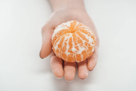 女人在白色背景下抱着成熟的整块去皮的橘子