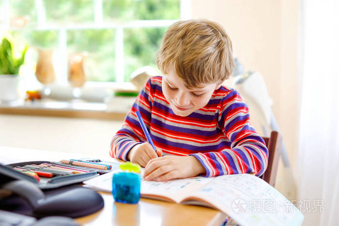 快乐微笑的小男孩在学校开学前的早晨在家做作业.小孩子在室内做运动.