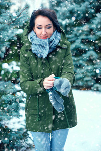 女人穿着手套在冬天的森林绿杉树和雪。