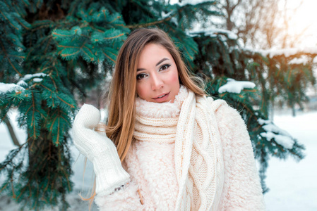 美丽的女孩冬天森林, 在背景云杉圣诞树上。包裹着针织围巾, 冬季自然中的强霜。穿着白色夹克和温暖的袖子。在森林中的城市以外休息。