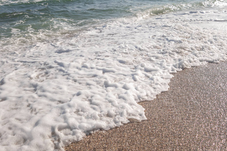 在阳光明媚的春天，海滨海滩和大海。 海浪在沙质和岩石海岸上奔跑。 选择性聚焦。