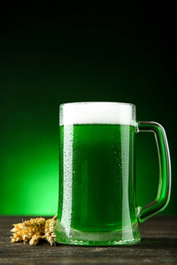 s Day. Green beer in mug with wheat ears on dark background
