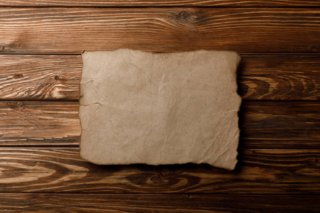 棕色的旧羊皮纸躺在木制的背景上