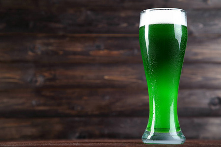 s Day. Glass of green beer on wooden background