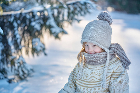 穿着毛衣的小女孩坐在雪地里微笑着
