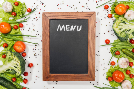 蕃茄莴苣叶黄瓜洋葱香料和大蒜的菜单字母的粉笔板的顶部视图