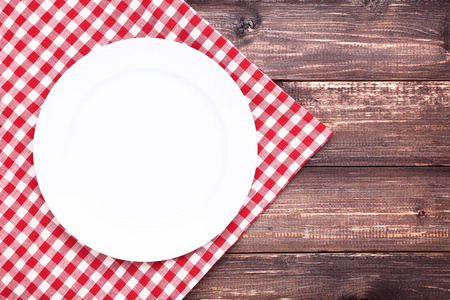 棕色桌子上有红色餐巾的白色盘子