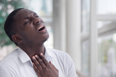  Portrait of ill black man suffering from sore throat due to col