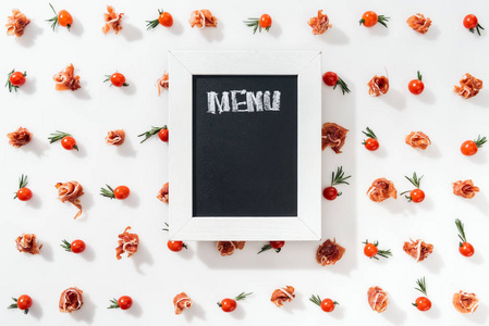 粉笔板的顶部视图，菜单字母在樱桃番茄，火腿香料和叶子中。