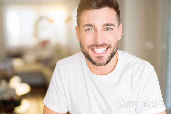 照片 年轻英俊的男人在家穿着休闲的白色t恤,脸上带着快乐和凉爽的