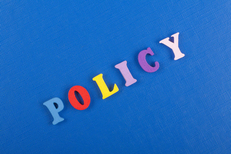 蓝色背景上的政策词由彩色ABC字母组成，木制字母，广告文本的复制空间。学习英语