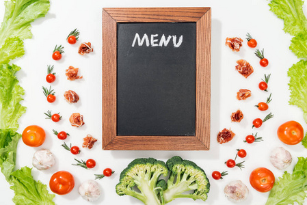 顶部的粉笔板，菜单字母在西红柿，生菜叶，意大利火腿，西兰花和大蒜。