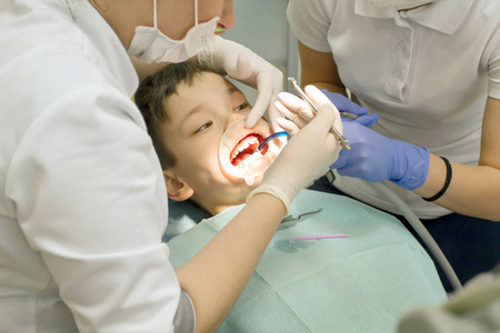 正畸医生检查男孩的嘴。 正畸医生把牙套放在牙齿上。 害怕牙医的男孩