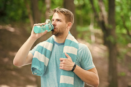 有运动外表的人拿着瓶子喝水。体育和健康的生活方式概念。运动员在阳光明媚的日子在体育场训练后喝水。人运动员在运动的衣裳训练室外