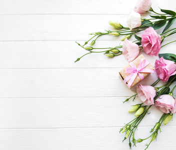 新鲜的粉红色的，木制背景的鲜花和礼品盒
