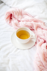 美丽的白色杯子，床上有茶，粉红色针织格子。在床上吃早餐。早上好。春天。