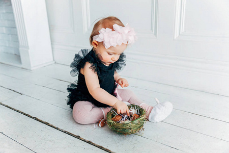 复活节时戴着春天花环的小女孩。 女孩拿着篮子，在家里装饰彩蛋，玩复活节彩蛋狩猎。 节日庆祝概念