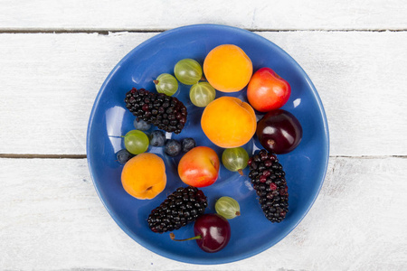 各种夏季新鲜浆果在一个碗里的乡村木制桌子。 抗氧化剂排毒饮食有机水果。 浆果