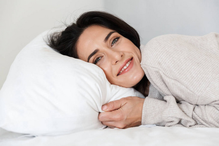 一张30多岁的美女躺在家里的白色枕头上的照片
