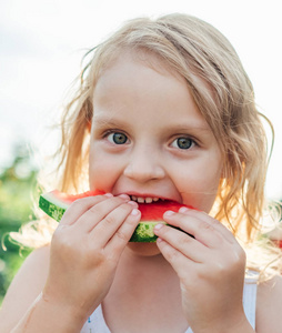 带西瓜的金发小女孩的肖像。 夏日户外儿童，带成熟的红西瓜