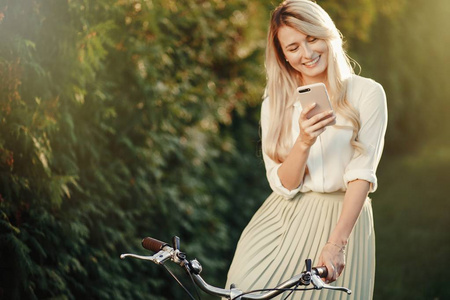 漂亮女孩的肖像与老式复古自行车使用智能手机。