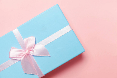 圣诞节新年生日情人节庆祝礼物浪漫的概念。 小礼品盒包着蓝色的纸，孤立在粉红色的糊上，五颜六色的时尚背景。 平躺顶视复印空间