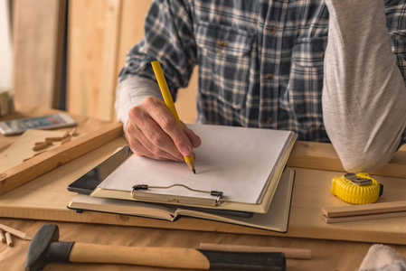木匠写剪贴板记事本纸项目笔记和做清单在小企业木工车间