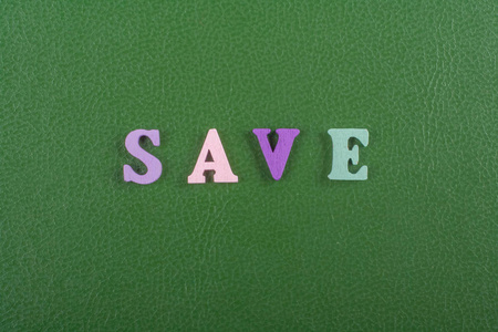 绿色背景上的单词由五颜六色的ABC字母组成，木制字母为广告文本复制空间。 学习英语