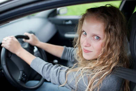 漂亮的年轻女人驾驶她的新车