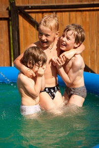三个孩子玩充气游泳池