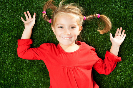在草地上微笑着的小女孩