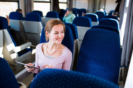 年轻女子乘火车旅行时使用她的平板电脑
